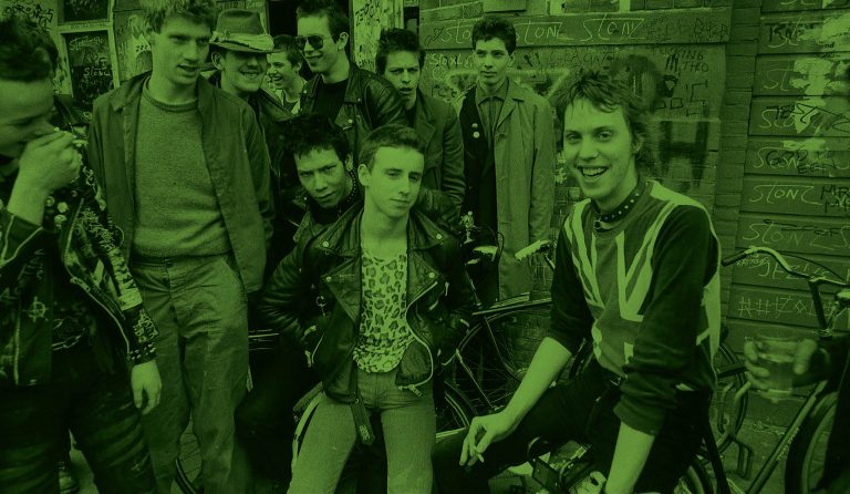 Een groep jongeren in punk-kleding poseert samen op een straat.