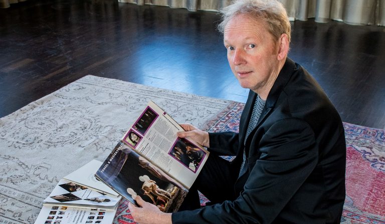Foto Henk Kuiper zittend op grond Stadsschouwburg met seizoenbrochures en Agenda's.
