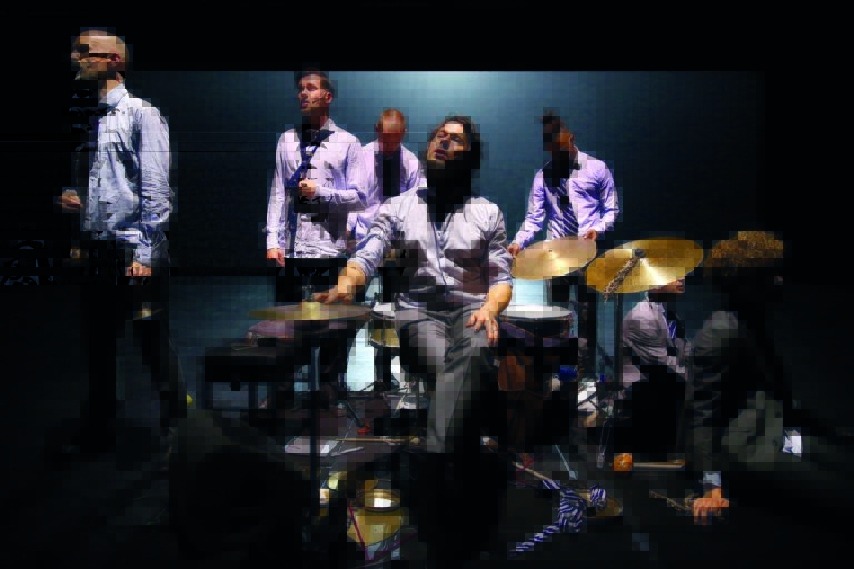 Een band speelt muziek op het podium, met muzikanten in formele kleding.