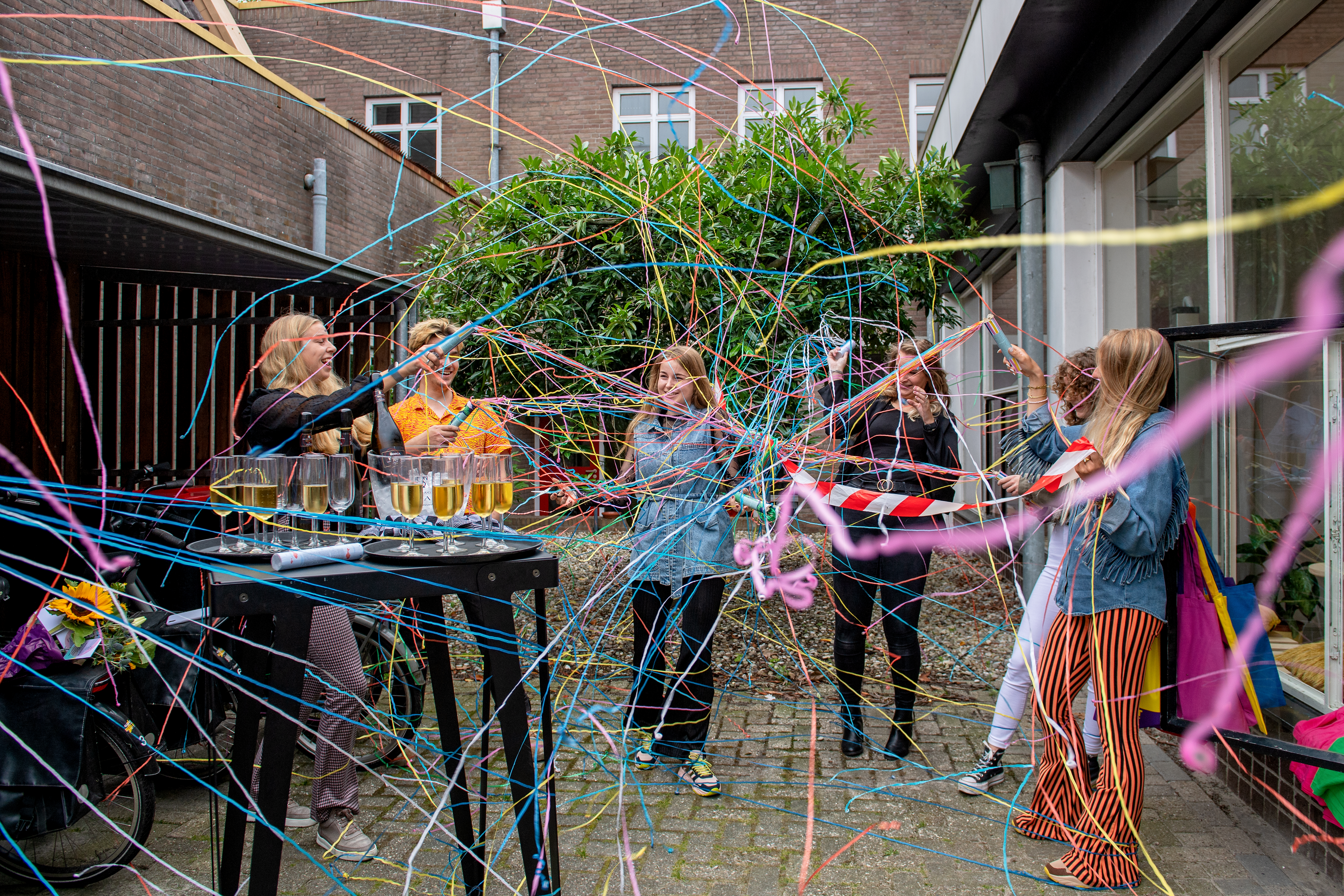 Deelnemers Crosswise vieren opening Hotspot met bubbels, vrolijk gekleurde confetti en terpentine.