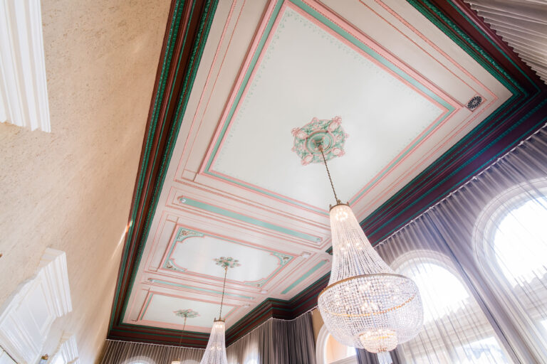 Decoratief plafond met gekleurde lijsten en twee hangende kroonluchters.