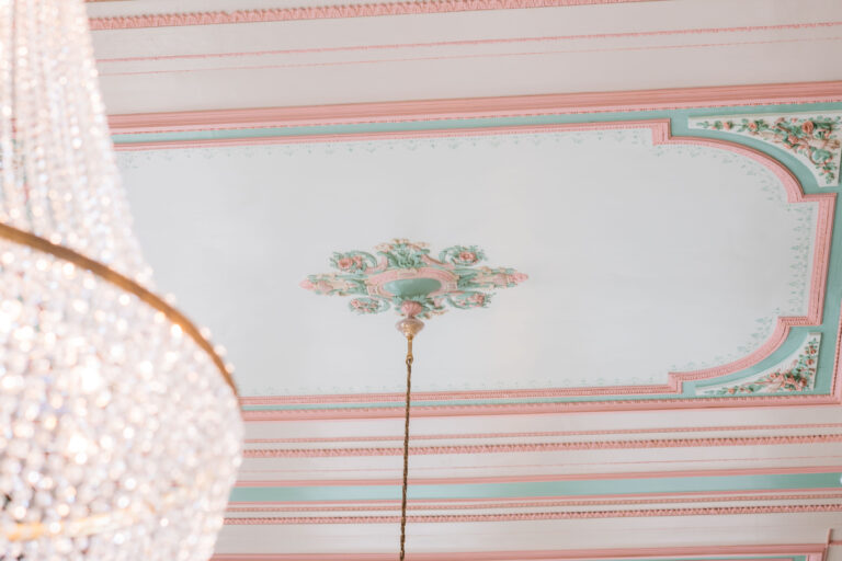 Decoratieve plafondschildering met groene en roze ornamenten.