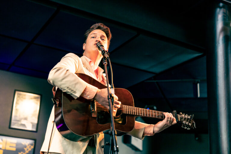Deelnemer open podium met bruine gitaar.