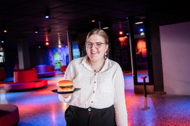 Deelnemer houdt een vegan broodje hamburger vast.