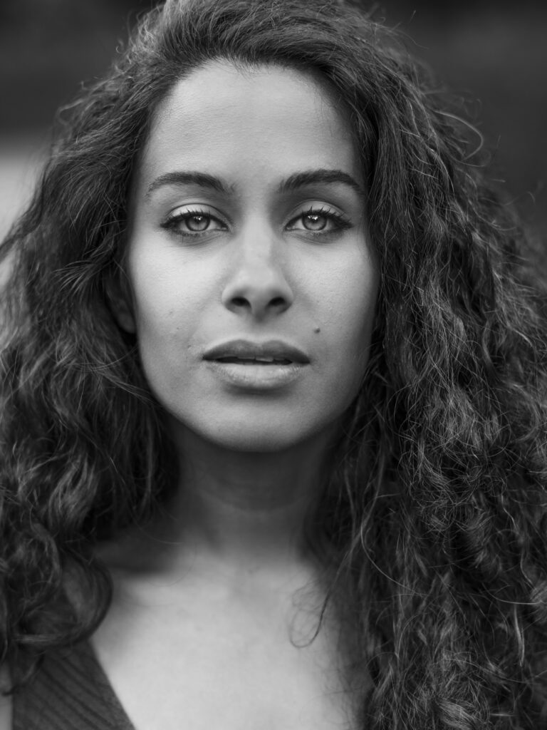 Zwart-witportret van een vrouw met krullend haar en intensieve ogen.