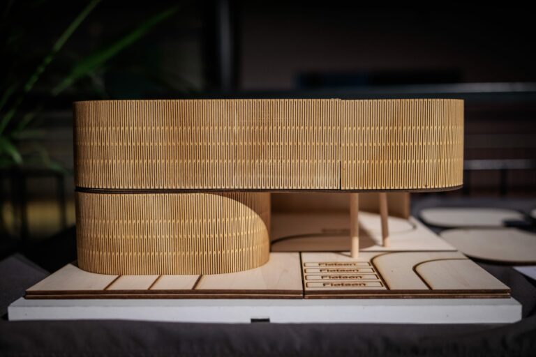 Een architectonisch model van een gebouw, gemaakt van hout met een moderne uitstraling.