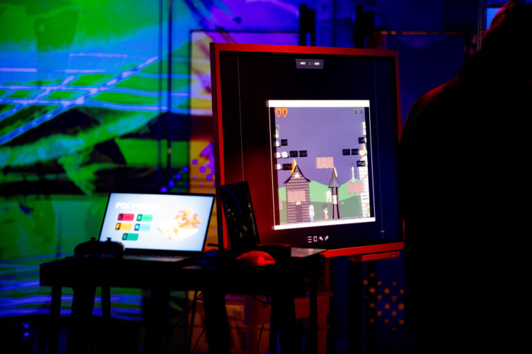 Een kleurrijke achtergrond met ervoor twee beeldschermen.