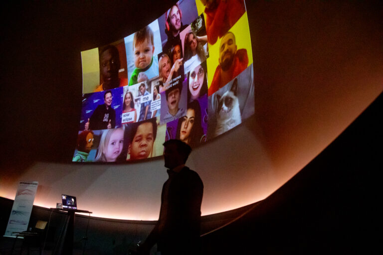 Silhouet van een man voor een beamer met allemaal kleurrijke, bekende memes.