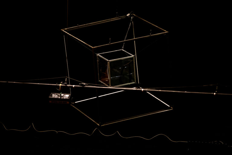 Zwart beeld met een vage, vierkante, ijzeren constructie in het midden.