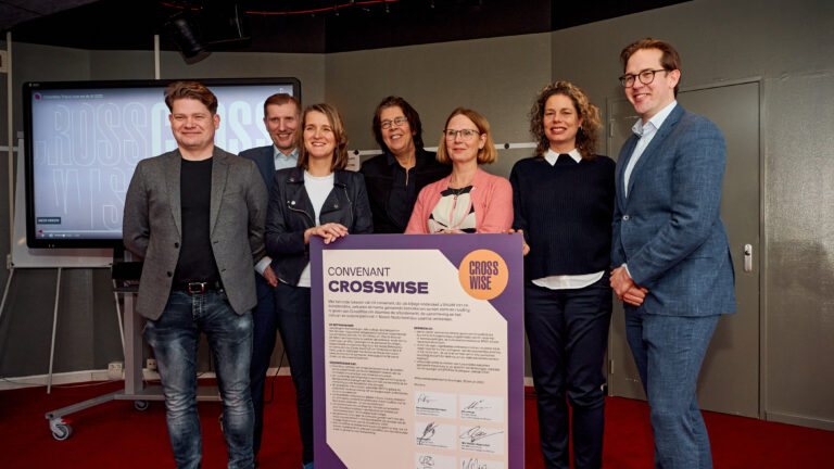 Groep mensen poseert samen voor een grote poster met de tekst