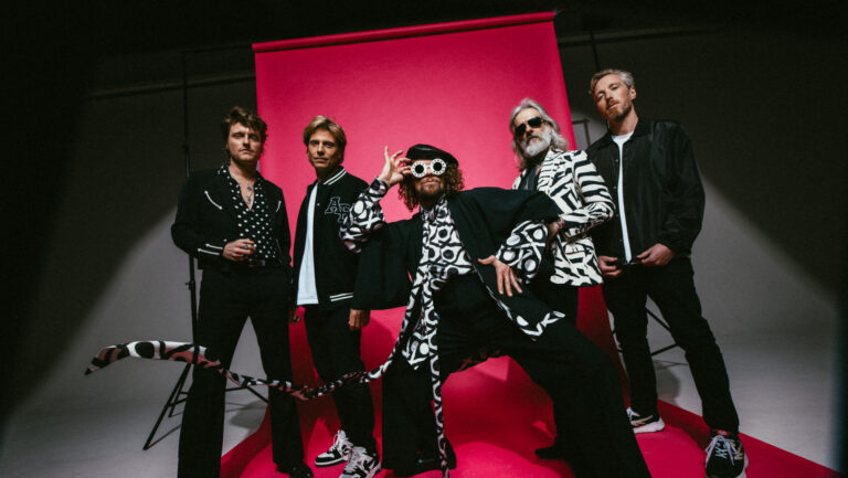 Vijf bandleden van di-rect poseren in zwartwit outfit voor een rood doek