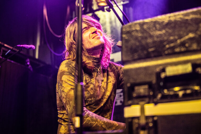 Een muzikant speelt enthousiast op een keyboard, omringd door kleurrijke verlichting.