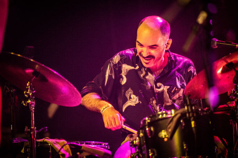 Een drummer speelt enthousiast op zijn drumkit tijdens een optreden.