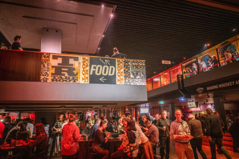 Een drukke eetgelegenheid met mensen die socializen, met een groot bord waarop 