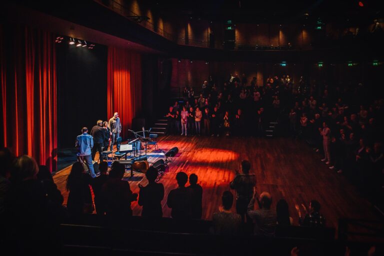 Een muzikaal optreden in een theater met een publiek dat van de show geniet.