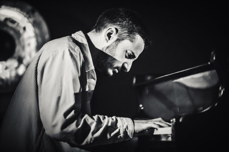 Een muzikant speelt geconcentreerd op een piano in zwart-wit.