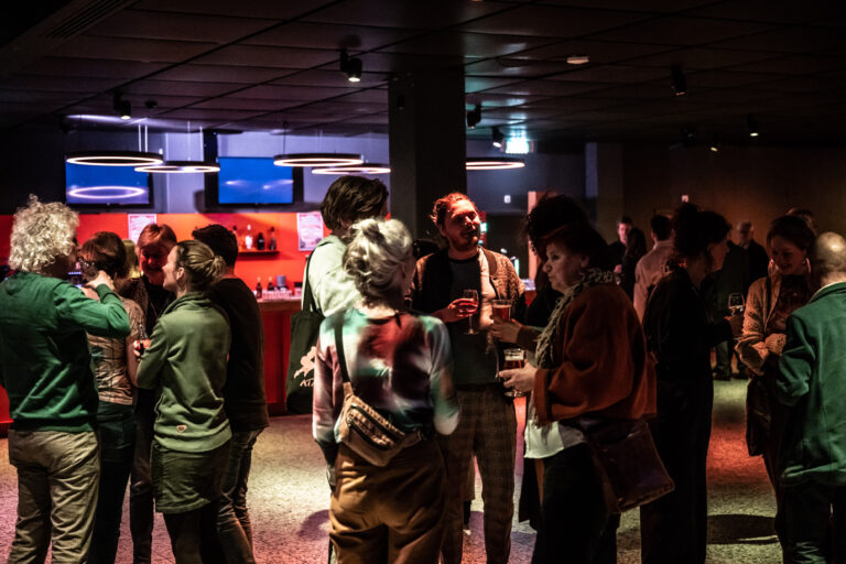 Foto van een ruimte van De Oosterpoort waar mensen aan het borrelen zijn.