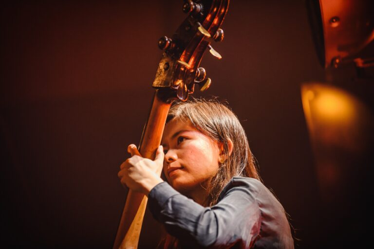 Een muzikante die geconcentreerd een contrabas bespeelt op het podium.