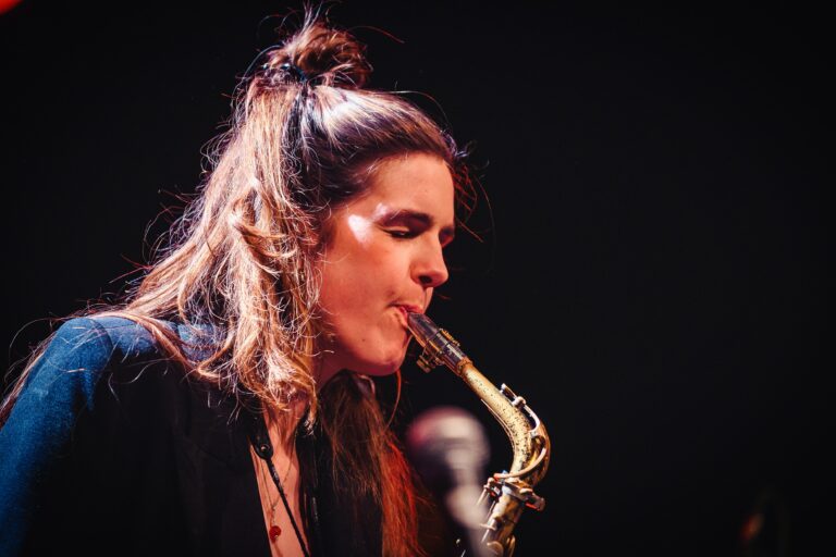 Een muzikant speelt op een saxofoon terwijl hij geconcentreerd kijkt.