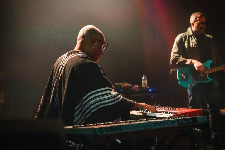 Een muzikant speelt op een keyboard tijdens een live optreden met kleurrijke verlichting.