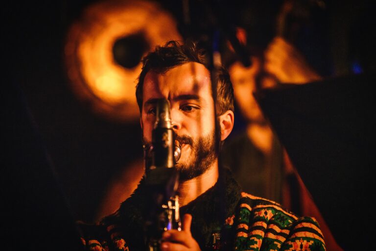 Een muzikant speelt een instrument terwijl hij in een sfeervolle omgeving is verlicht.