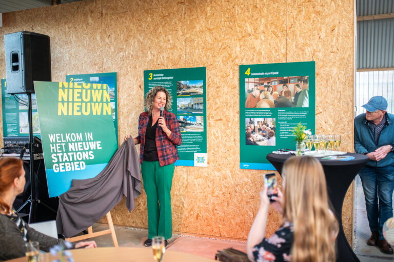 Opening informatiecentrum stationsgebied - wethouder Kirsten de Wrede onhult in de loods een bord met de huisstijl van het nieuwe stationsgebied