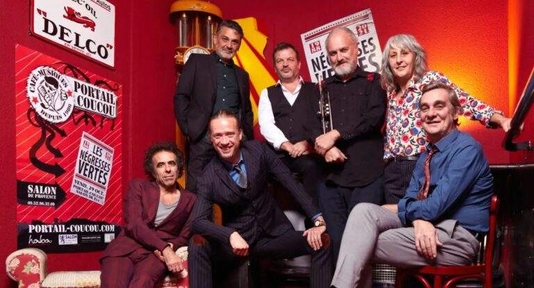 Een groep mensen poseert samen voor een rode achtergrond met muzikale elementen.