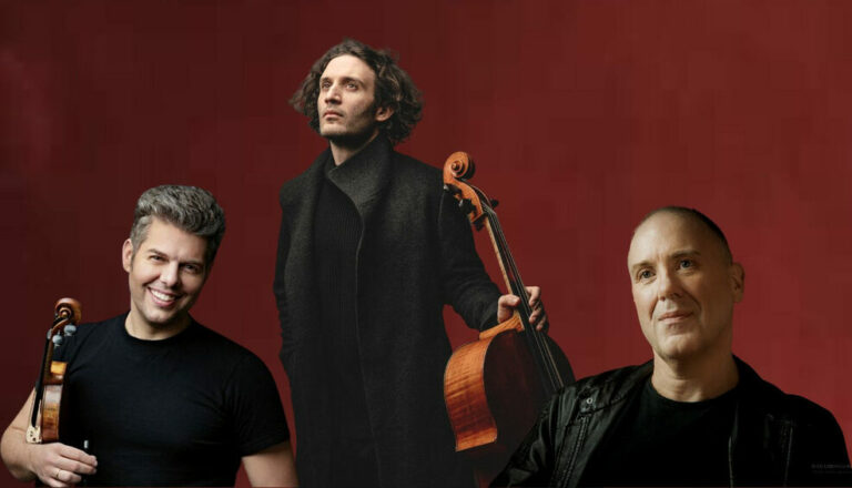 De drie solisten in het zwart gekleed voor een donkerrode achtergrond. Barnabás met zijn viool in de hand en Nicolas met zijn cello.