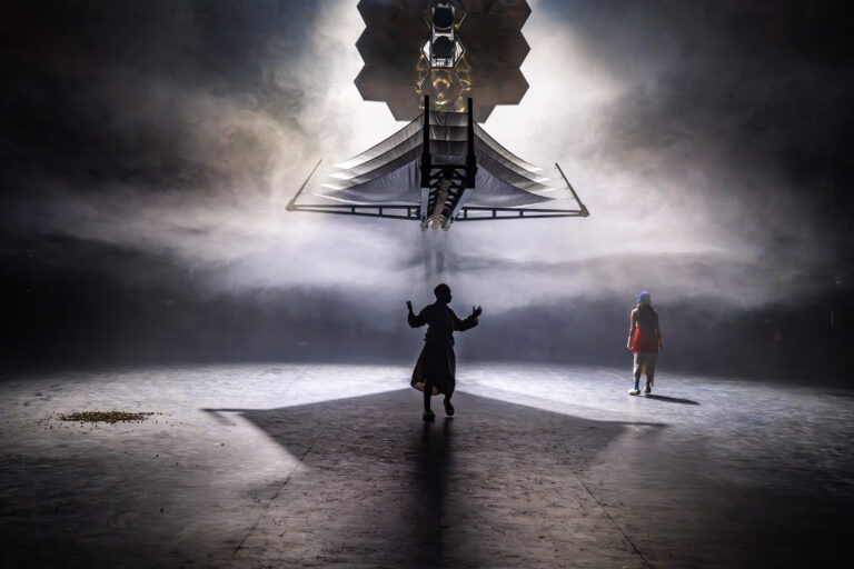 Silhouet van een persoon onder een grote satelliet