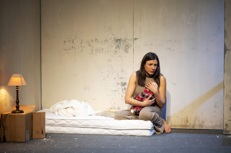 actrice Alejandra Theus zittend op een matras met een baby in haar armen