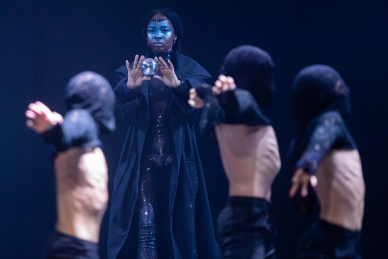 Vrouwelijke danseres in zwarte mantel toont een glazen bol