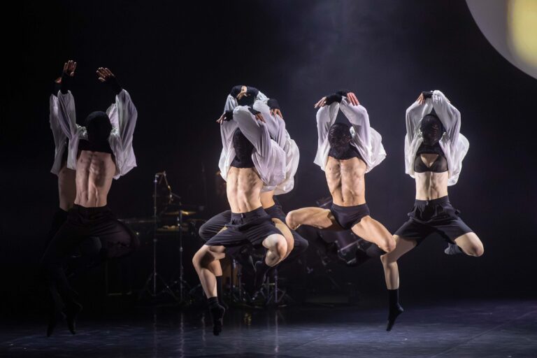 Dansers met zwarte maskers springen in de lucht