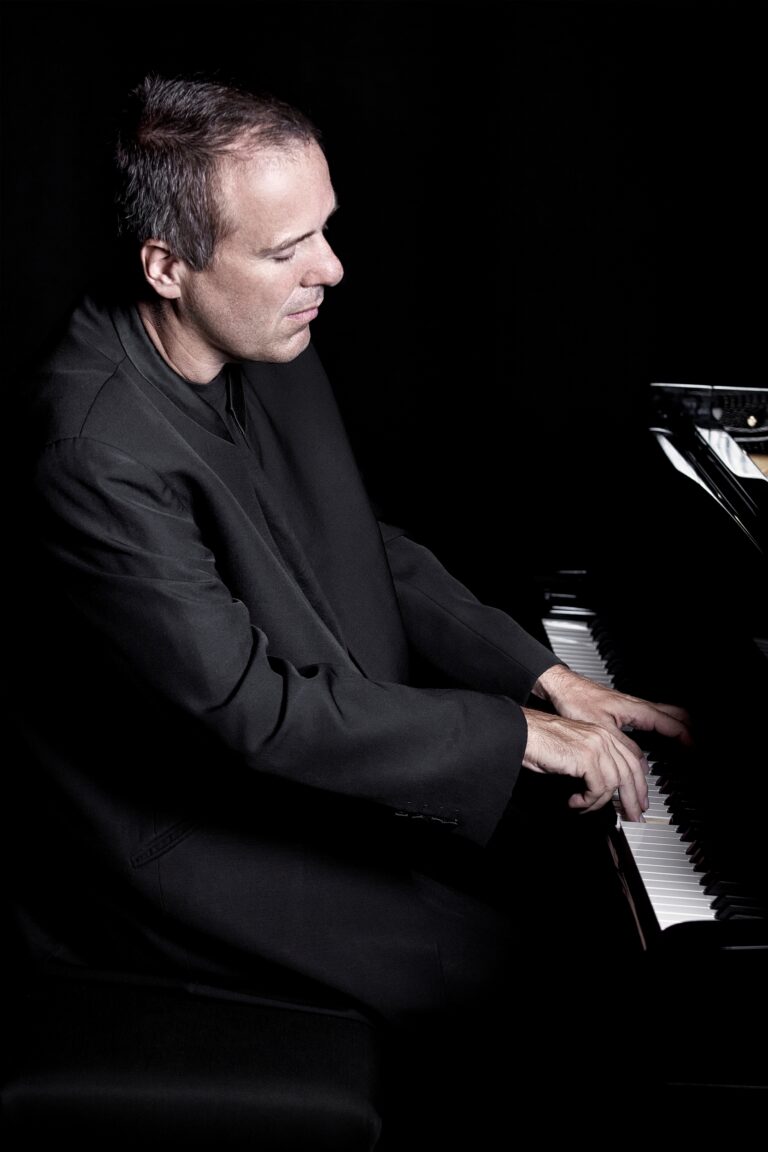 Een man speelt piano in een donkere omgeving.