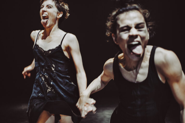 Twee dansers hand in hand met hun tong naar buiten