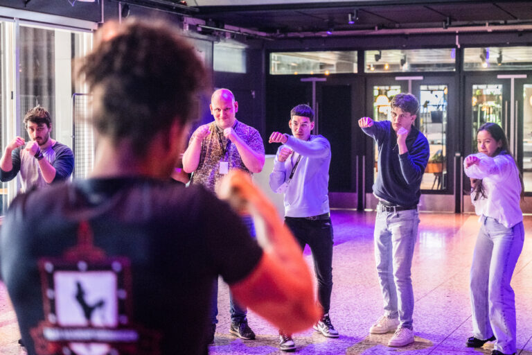 Deelnemers doen in de pauze bij de Hackathon aan kickboksoefeningen.