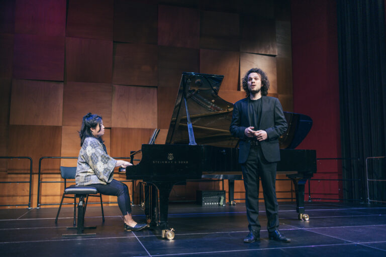 Meisje spelend op een vleugel, man staat er naast te zingen.