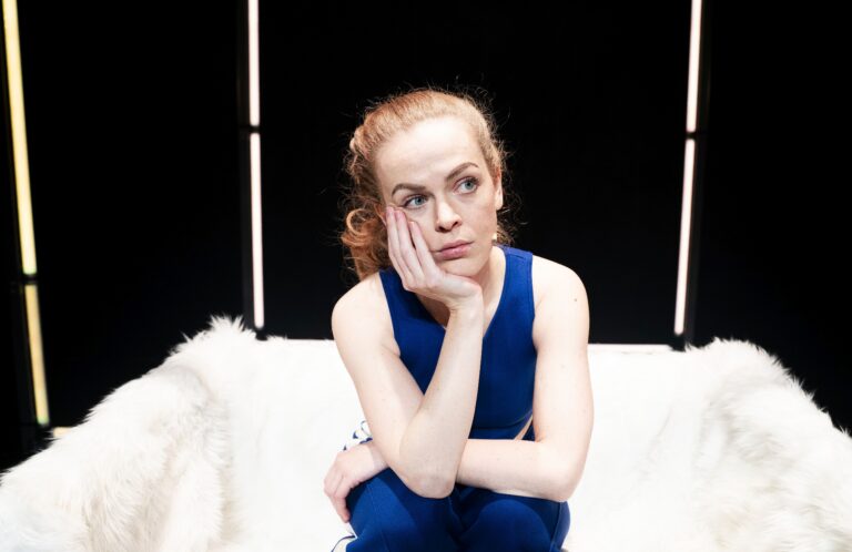 Lisa Ostermann zit peinzend met haar hand onder haar kin op een witte fauteuil