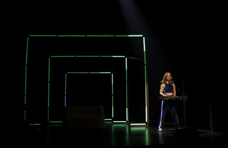 Lisa Ostermann staat in een decor van drie steeds groter wordende groene vierkanten