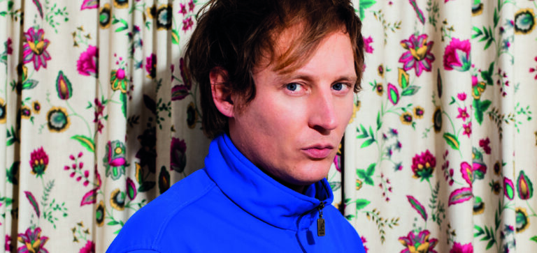 Lucky Fonz in een blauw jasje voor een bloemetjesgordijn