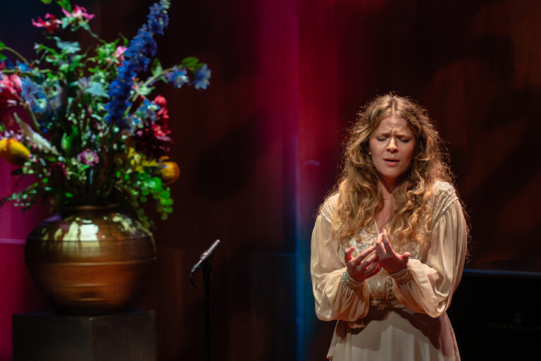 vrouw zingt en heeft handen gevouwen voor een rode achtergrond