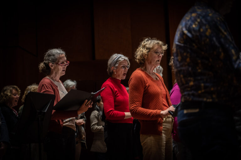 Drie vrouwen in felgekleurde shirts staan te zingen