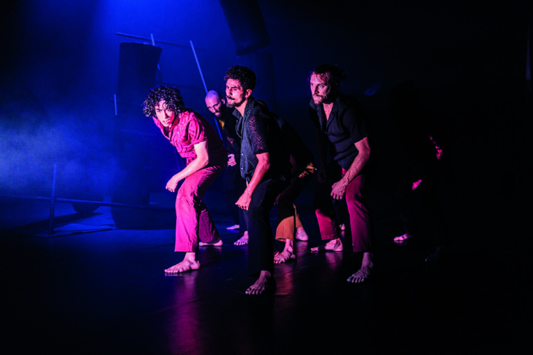 Dansers stappen in het licht vanuit een donkere achtergrond