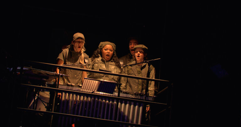 Acteurs in legerkleding staan achter een bureau