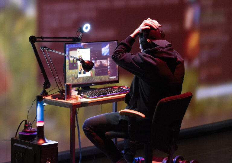 Een persoon zit achter een computer met een gefrustreerde houding, terwijl hij zijn hoofd in zijn handen houdt.