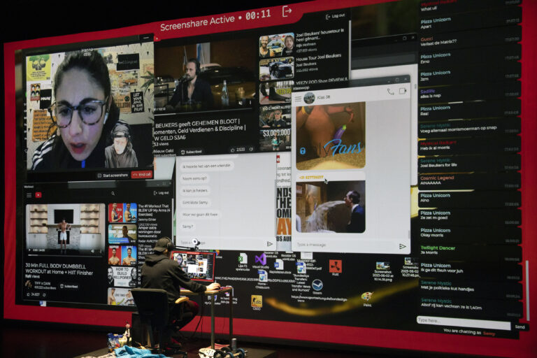 Een persoon zit achter een computer terwijl ze een groot scherm met meerdere vensters en afbeeldingen bekijken.