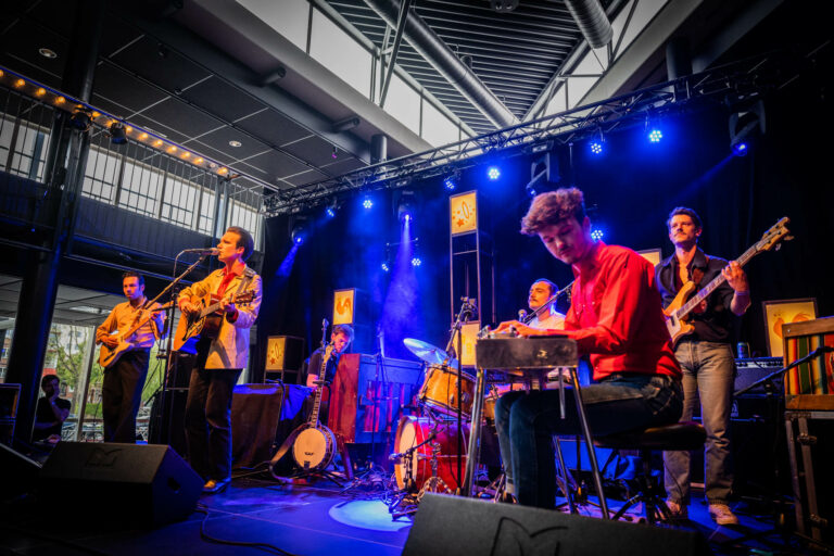 Een band voert een live optreden op een podium met blauwe verlichting.