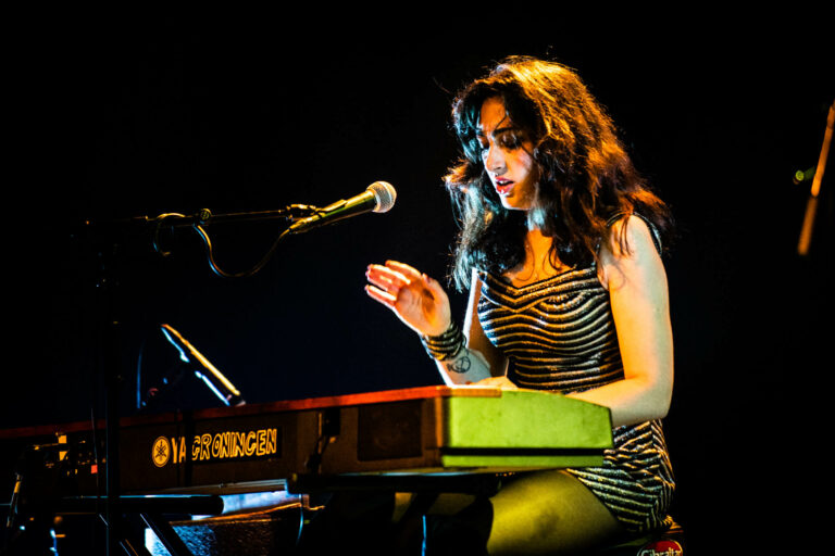 Een muzikante speelt op een keyboard terwijl ze geconcentreerd naar de muziek kijkt.