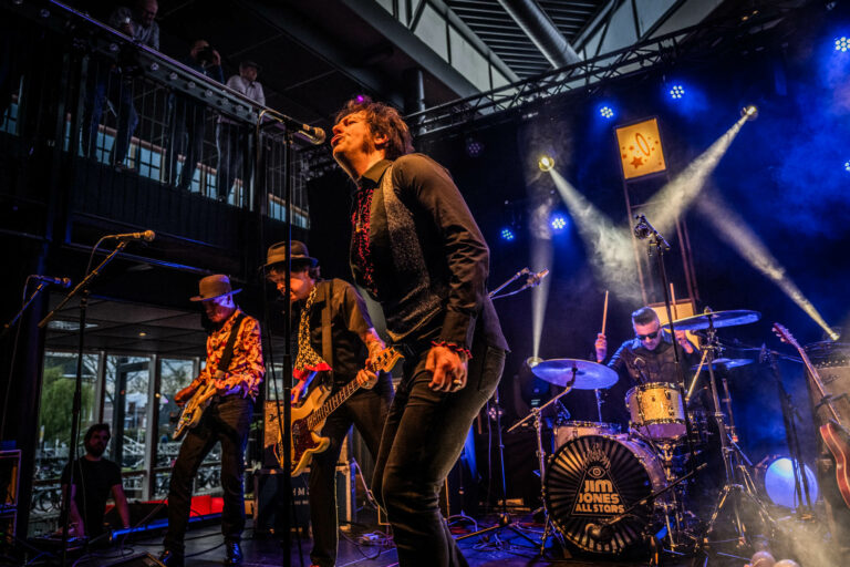 Een band voert een energieke liveoptreden uit op een podium met felle verlichting.