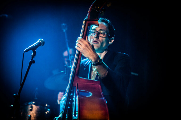 Een muzikant speelt op een gitaar met een dramatische belichting tijdens een optreden.