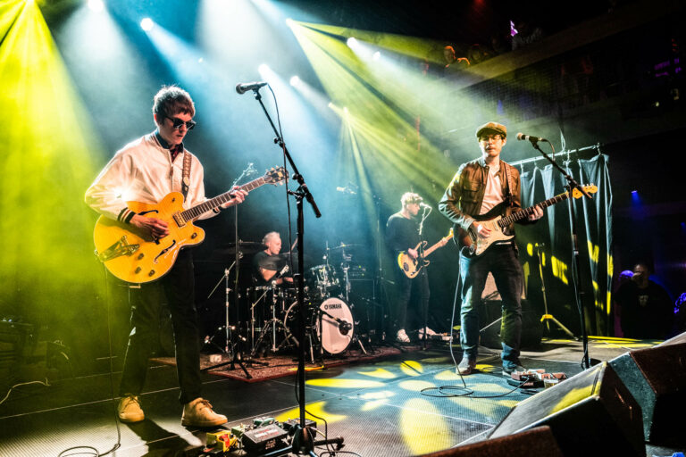 Een live band speelt op een podium met kleurrijke verlichting.